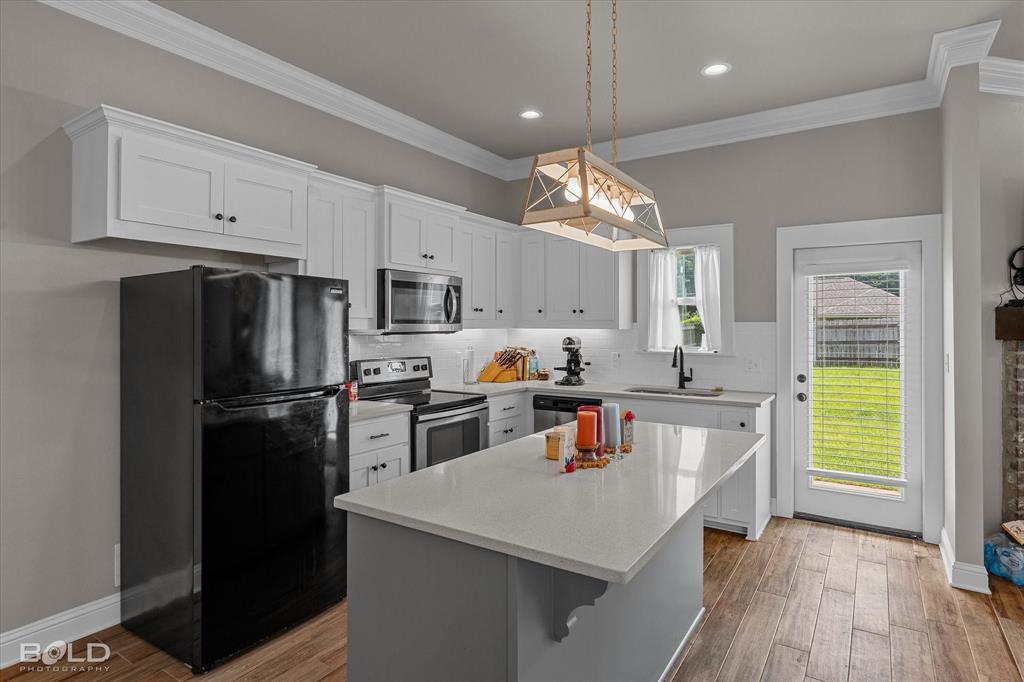 6896 Bethany Reed Circle Blanchard, LA 71107 - Photo 22 of 37 Kitchen featuring white cabinetry, wood-finish flooring, a central island with a light-colored countertop, and a glass-paned door