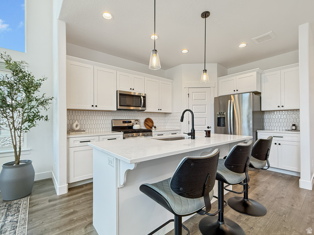 641 Desert Willow Drive Mapleton, UT 84664 - Photo 9 of 41 Kitchen featuring tasteful backsplash, stainless steel appliances, white cabinets, and a kitchen breakfast bar