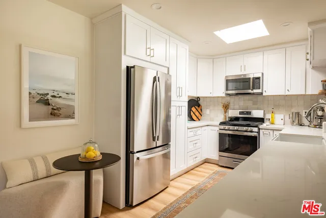 a kitchen with stainless steel appliances granite countertop a refrigerator a stove a sink and dishwasher with white cabinets