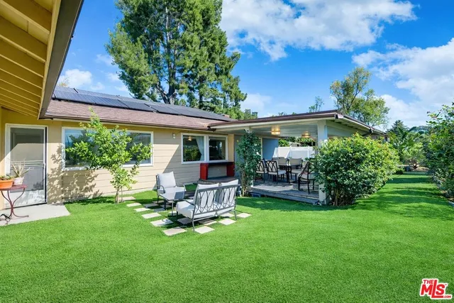 a view of a chair and table in backyard of the house