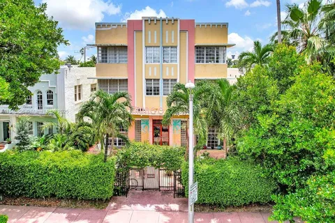 a front view of a multi story residential apartment building with a yard and potted plants