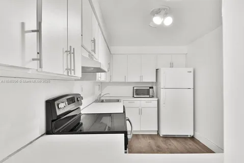 a kitchen with a refrigerator and white cabinets