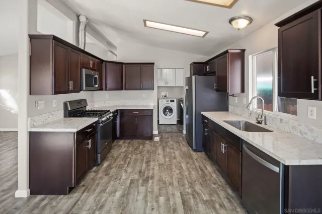 a large kitchen with stainless steel appliances a sink and a refrigerator