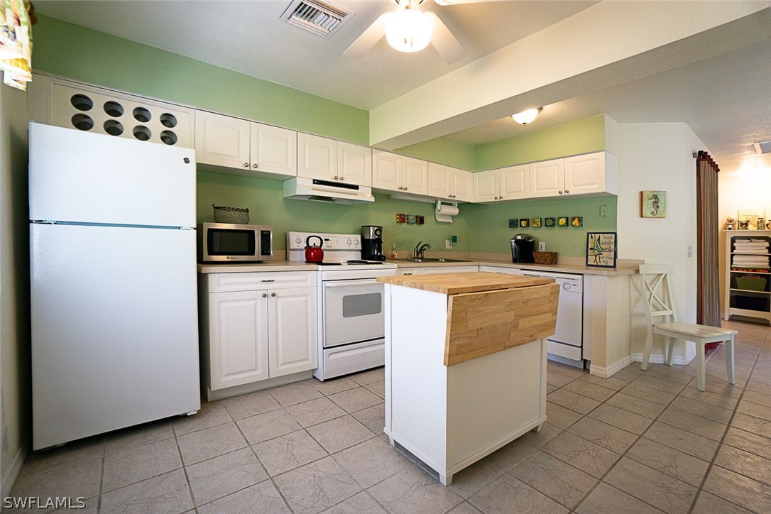 849 Beach Road Sanibel, FL 33957 - Photo 4 of 14 a kitchen with white cabinets and white appliances