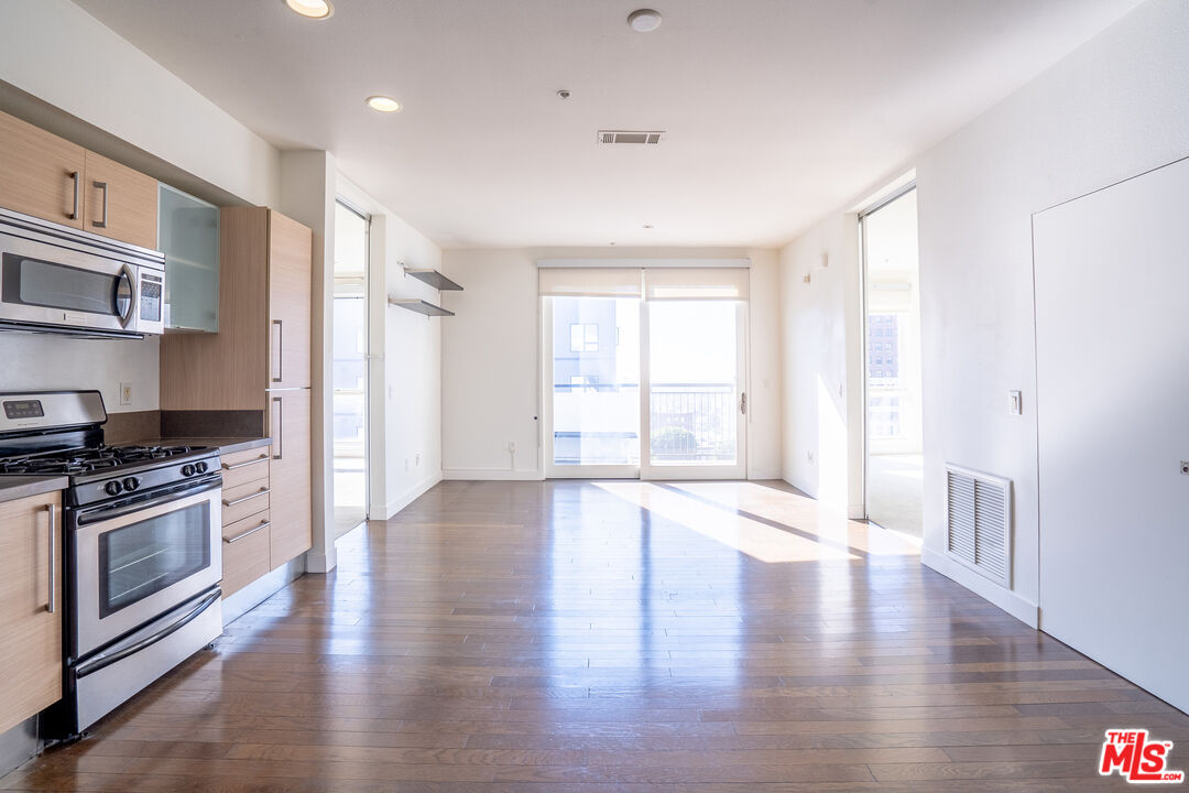a view of an empty room with a window and wooden floor