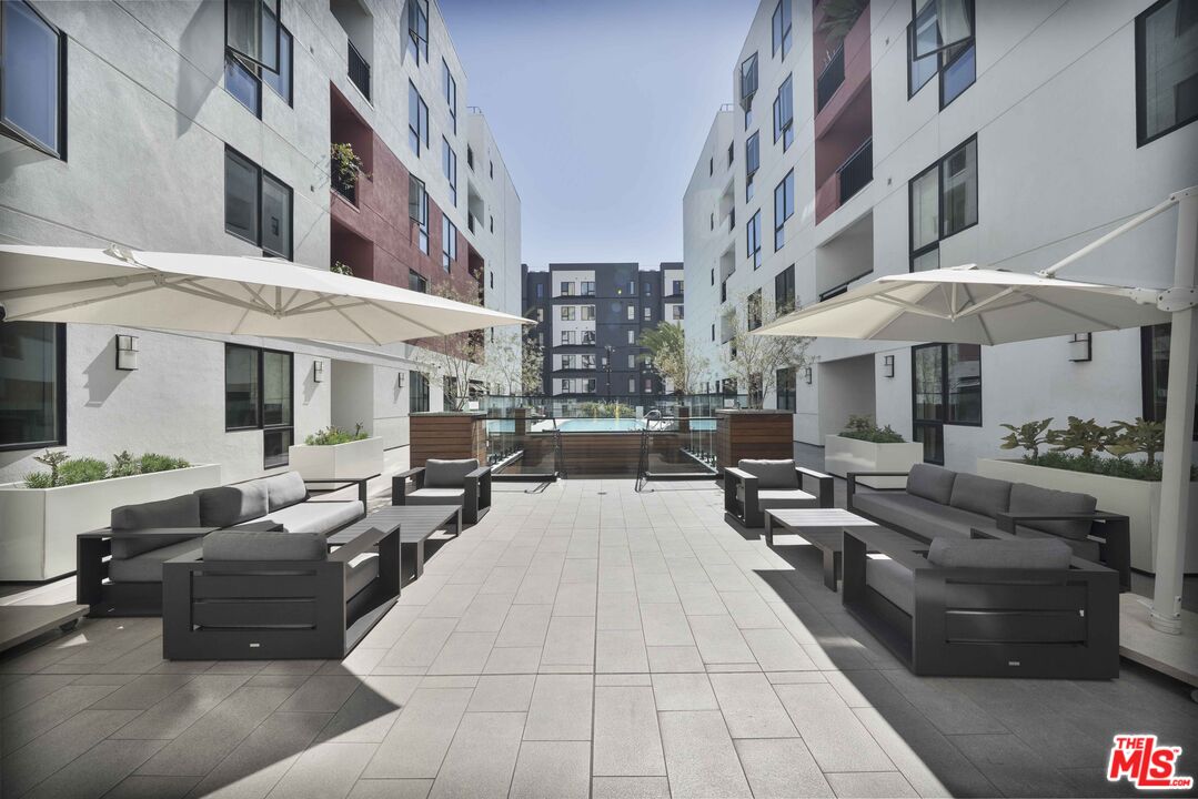 1234 Wilshire Boulevard, Unit 517 Los Angeles, CA 90017 - Photo 17 of 17 a view of a patio with couches table and chairs under an umbrella with wooden floor