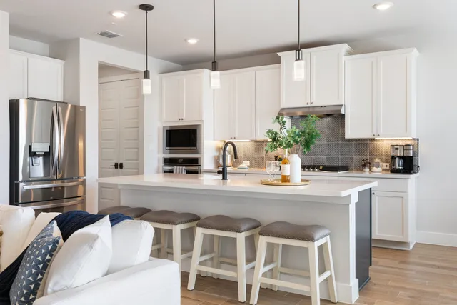 a kitchen with stainless steel appliances a dining table chairs sink and microwave