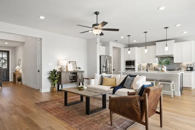 a living room with furniture kitchen view and a chandelier
