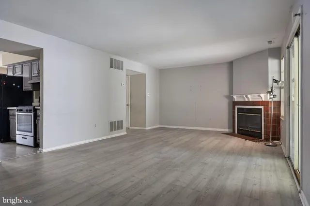 a view of empty room with kitchen and fireplace