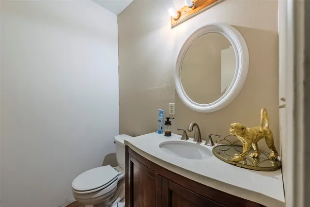 a bathroom with a granite countertop toilet a sink and a mirror