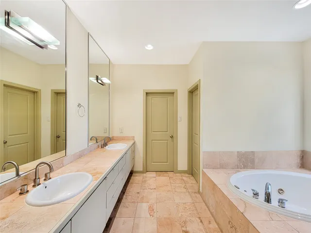 a bathroom with a granite countertop tub sink and mirror