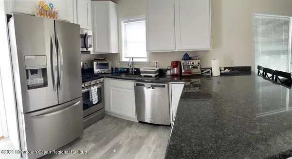 a kitchen with stainless steel appliances a refrigerator a sink a stove and white cabinets