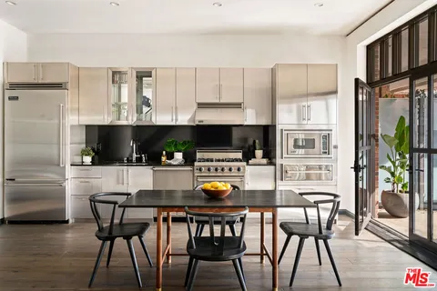a kitchen with stainless steel appliances a dining table chairs and granite counter tops