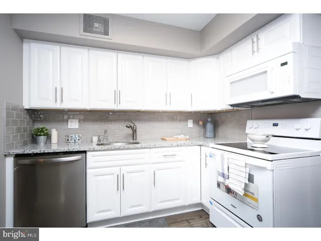 a kitchen with granite countertop white cabinets and white appliances