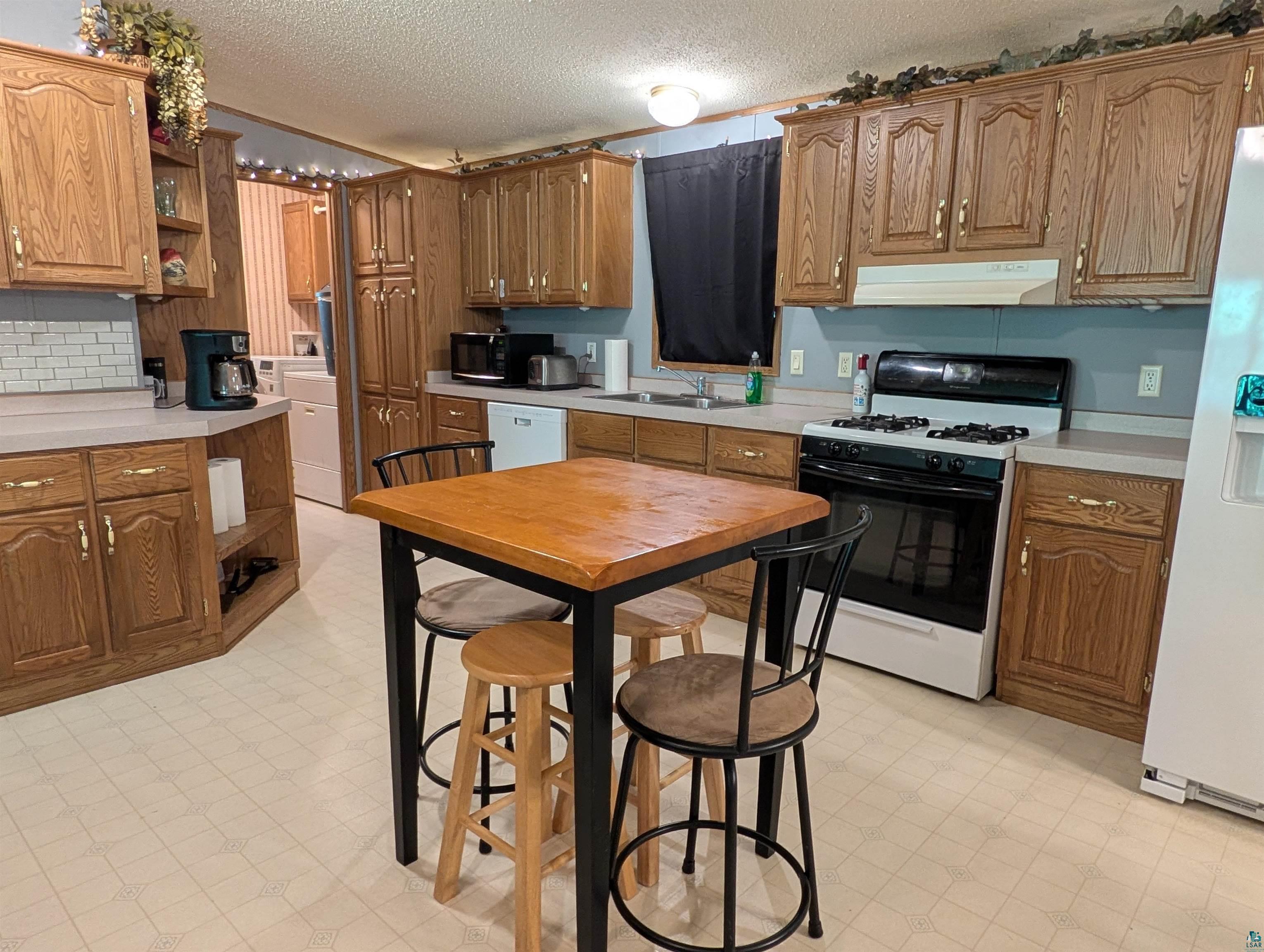 3945 Maple Street Kettle River, MN 55757 - Photo 4 of 41 Kitchen featuring wood-finish cabinetry, light-toned countertops, a white gas range, and light-toned flooring