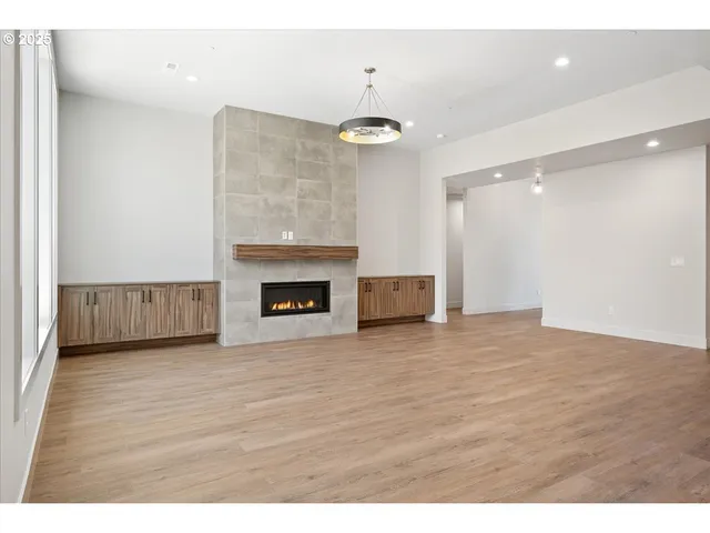 a view of an empty room with wooden floor and a fireplace