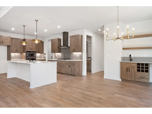 a open kitchen with kitchen island a refrigerator a stove a sink and dishwasher with wooden floor