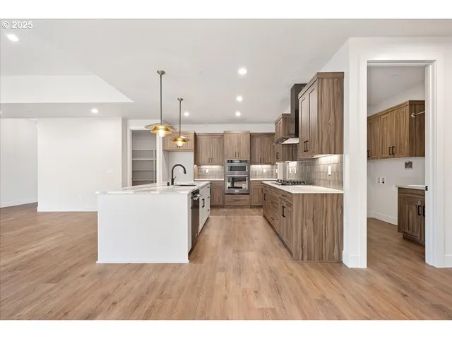 a kitchen with stainless steel appliances kitchen island wooden floors and white cabinets