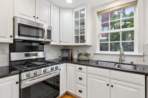 a kitchen with granite countertop white cabinets stainless steel appliances and a sink