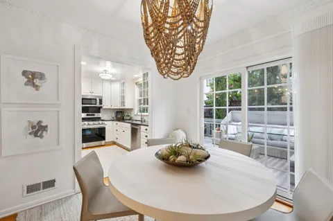a kitchen with stainless steel appliances a dining table and chairs with wooden floor