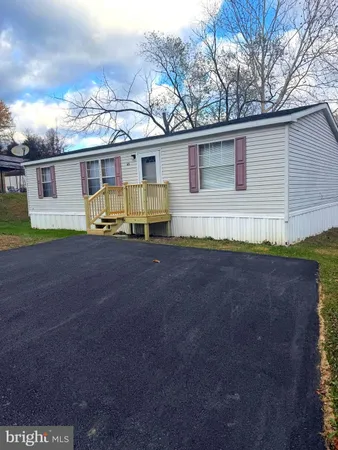 a front view of house with yard and trees in the background