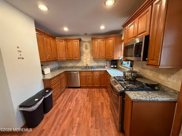 a kitchen with granite countertop stainless steel appliances a sink stove refrigerator and cabinets