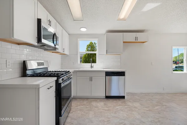 a kitchen with stainless steel appliances a stove microwave and sink