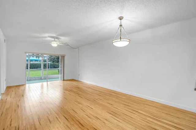 a view of a livingroom with wooden floor a ceiling fan and windows