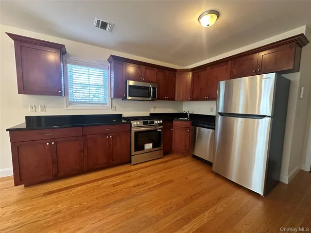 a kitchen with wooden floors stainless steel appliances and a window