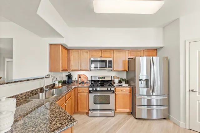 a kitchen with stainless steel appliances granite countertop a stove a sink and a refrigerator