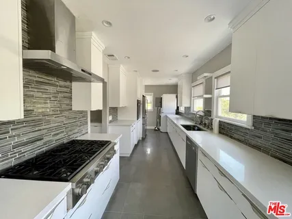 a large white kitchen with sink and stainless steel appliances