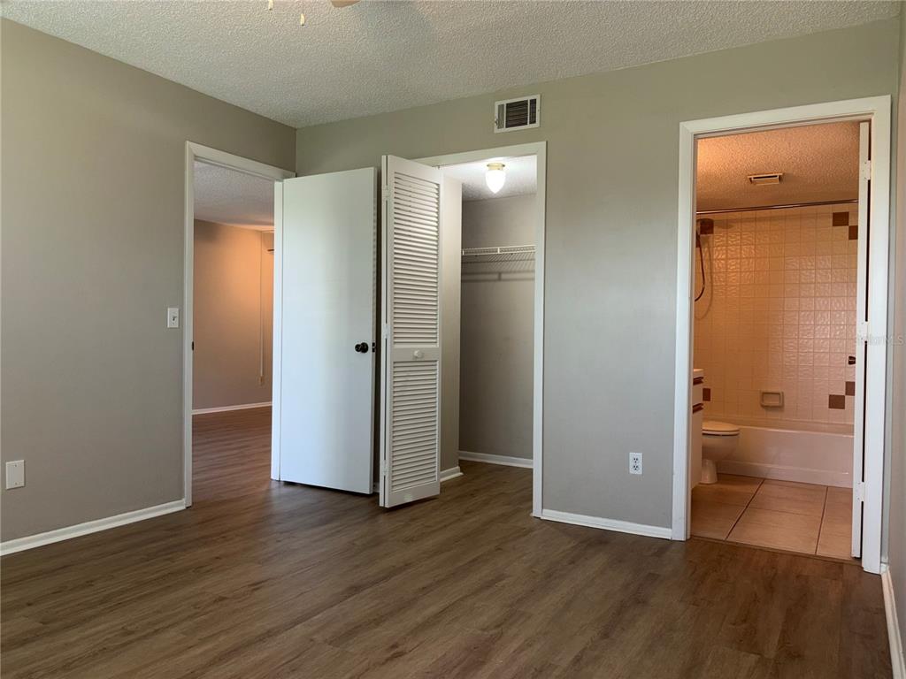 26485 Rampart Boulevard, Unit D1 Punta Gorda, FL 33983 - Photo 9 of 29 an empty room with wooden floor and a bathroom