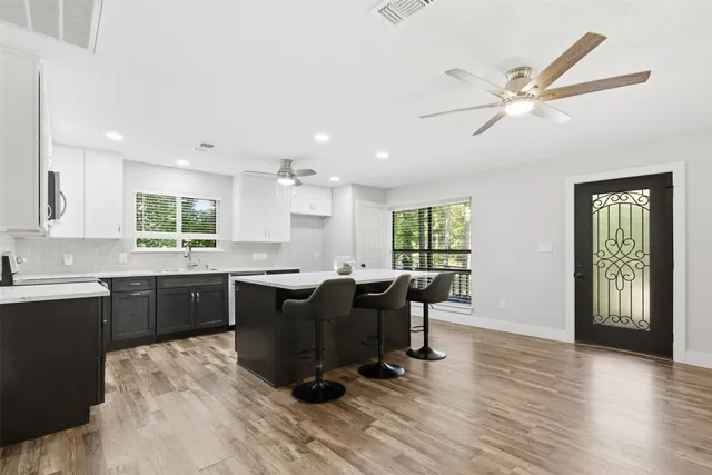 a hall with kitchen island a stove a wooden floors and a large window