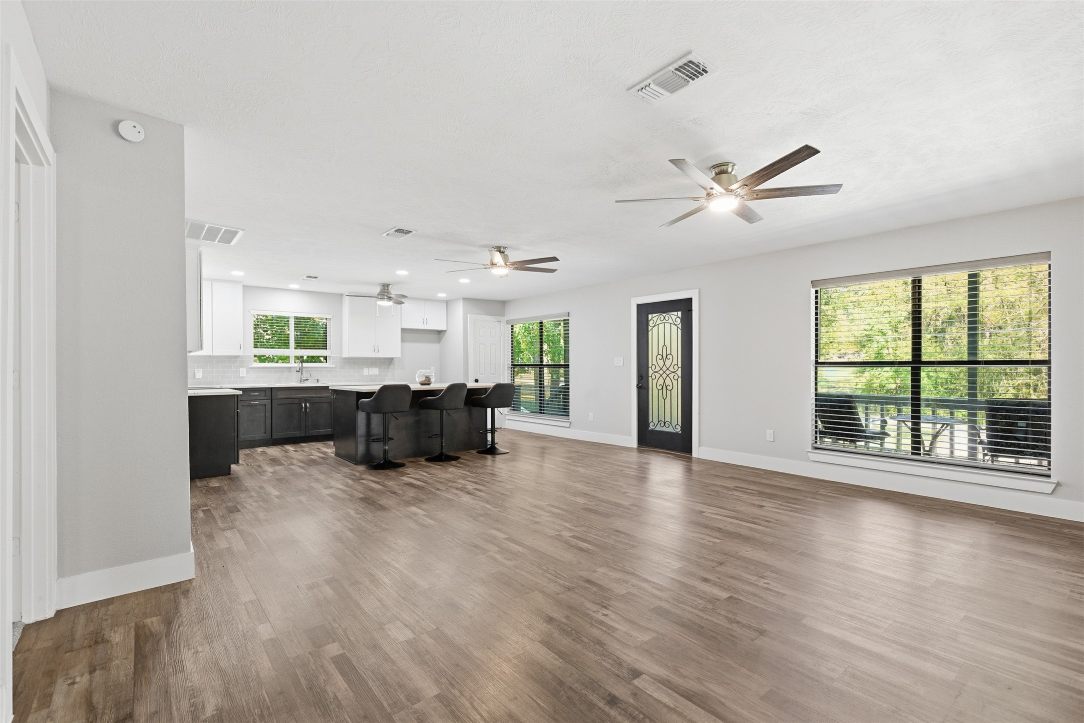 94 Gov Bell Drive Point Blank, TX 77364 - Photo 16 of 49 Spacious and bright living area seamlessly connected to the kitchen for an open, inviting flow. Enjoy modern flooring, abundant natural light, and serene views of lush greenery — plus a convenient side door with a built-in doggy door for your furry friend.
