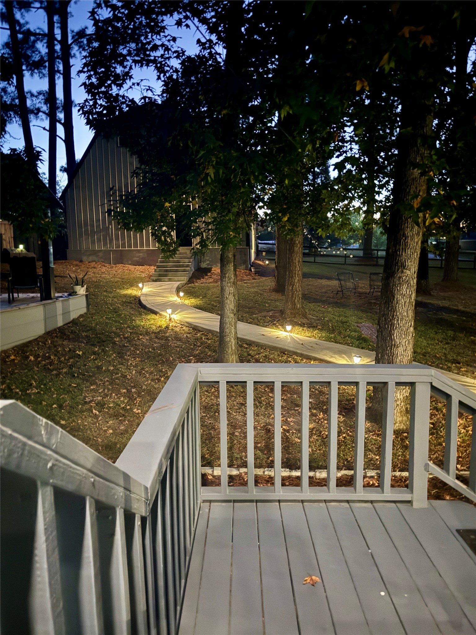 94 Gov Bell Drive Point Blank, TX 77364 - Photo 35 of 49 Experience the magic of 94 Gov Bell Dr at night! Beautifully remodeled with lights highlighting every angle, this home glows against a stunning backdrop of greenery. From the charming wraparound porch to the scenic path leading to the oversized garage and gazebo, every detail is designed for comfort, style, and outdoor enjoyment — perfect for relaxing evenings or entertaining under the stars.