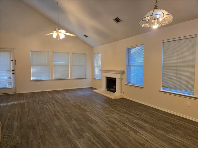 a view of an empty room with wooden floor fireplace and a window