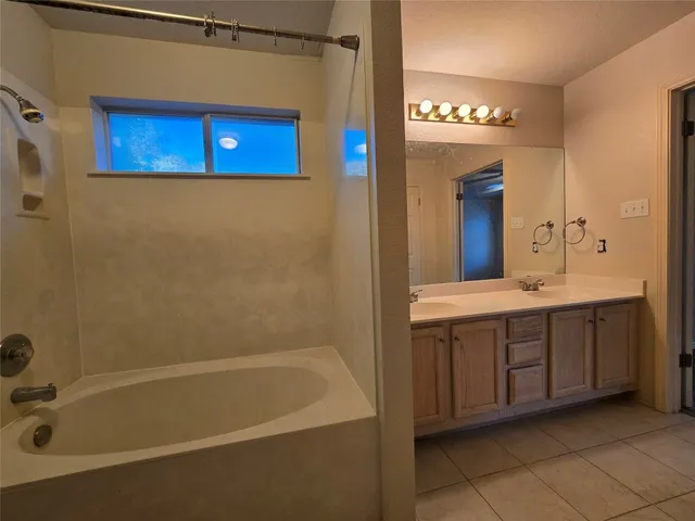 a bathroom with a tub a sink and a large mirror