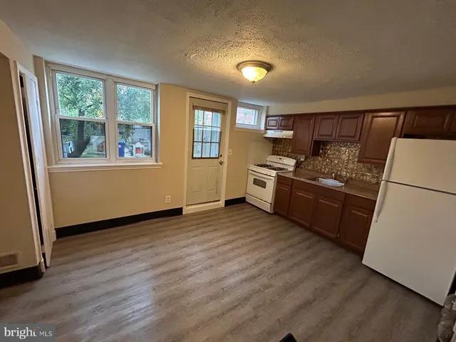 a kitchen with granite countertop a refrigerator stove top oven and sink