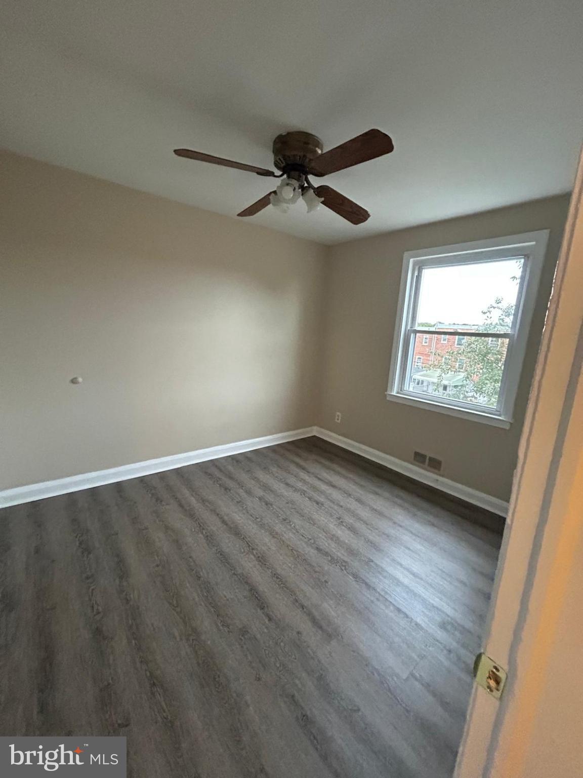 4116 Raymonn Avenue Baltimore, MD 21213 - Photo 9 of 16 an empty room with wooden floor fan and windows