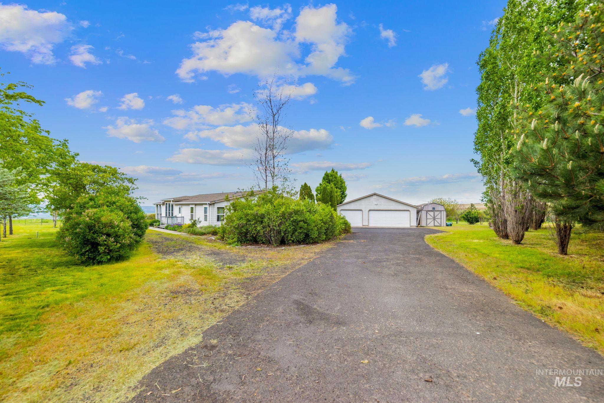 37989 Rosenkrantz Road Lewiston, ID 83501 - Photo 6 of 50 Paved driveway leading to a detached garage with two bays, accompanied by an additional storage shed