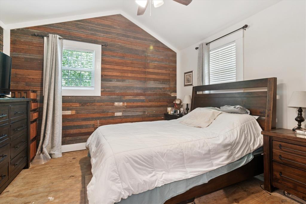 1102 West 12th Street Bonham, TX 75418 - Photo 12 of 27 Bedroom with wooden walls, vaulted ceiling, a ceiling fan, and light wood-style floors