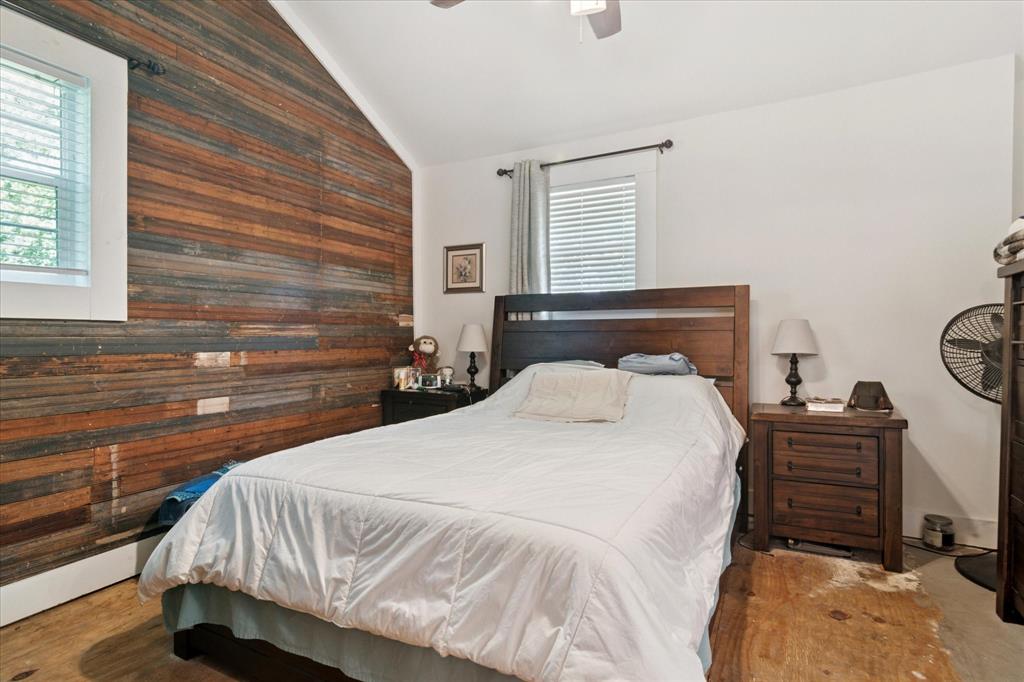1102 West 12th Street Bonham, TX 75418 - Photo 13 of 27 Bedroom with vaulted ceiling, wood walls, and a ceiling fan