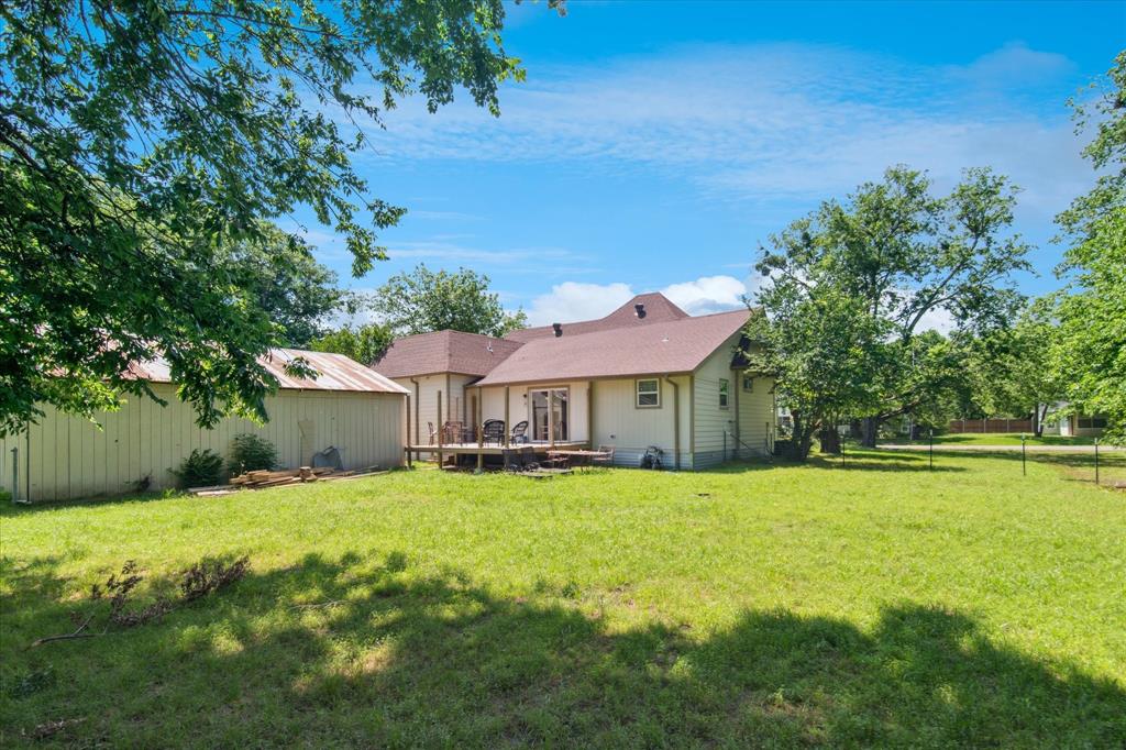 1102 West 12th Street Bonham, TX 75418 - Photo 18 of 27 Rear view of house featuring a lawn and a shingled roof