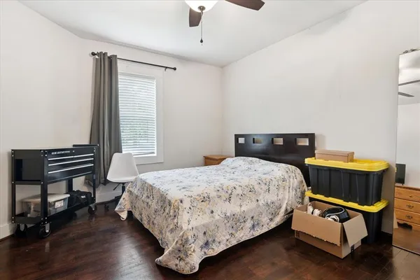 a bedroom with a bed chair and wooden floor