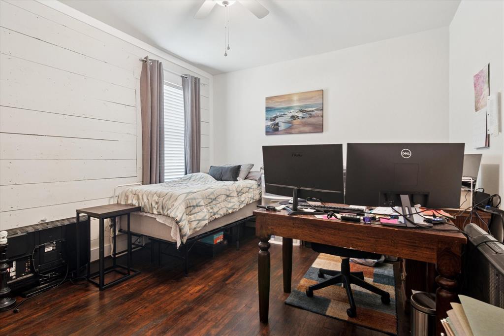 1102 West 12th Street Bonham, TX 75418 - Photo 24 of 27 Bedroom featuring an office area, dark wood-style flooring, ceiling fan, and wood walls