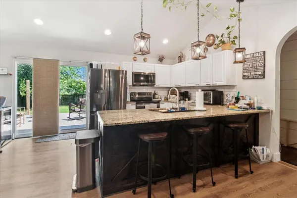 a kitchen with kitchen island granite countertop a sink cabinets and wooden floor
