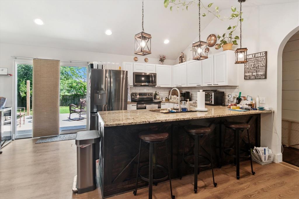 1102 West 12th Street Bonham, TX 75418 - Photo 5 of 27 Kitchen with a kitchen breakfast bar, a peninsula, white cabinets, arched walkways, and stainless steel appliances