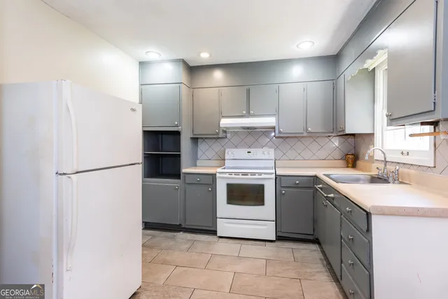 a kitchen with a white stove refrigerator and cabinets