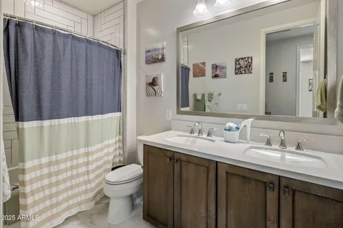 a bathroom with a granite countertop sink toilet a mirror a vanity and shower