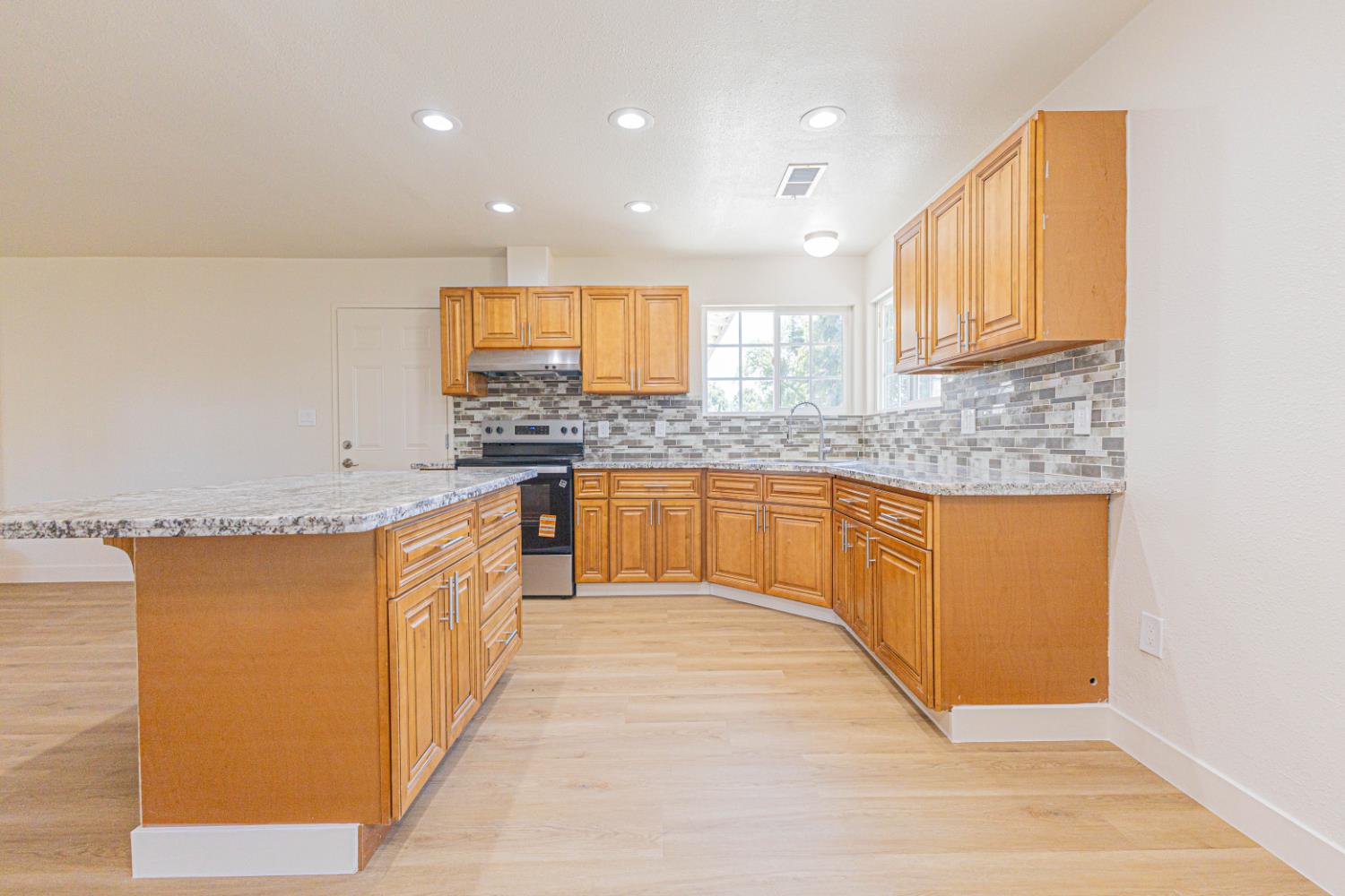 17925 Rodeo Drive Madera, CA 93638 - Photo 7 of 26 a large kitchen with stainless steel appliances granite countertop a sink and cabinets